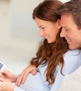 Ein Paar im Zillertal Hotel Theresa betrachtet Ultraschallbilder während ihres Urlaubs mit Babybauch