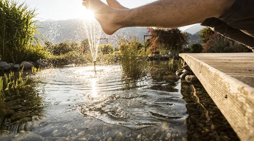 Aussenbereich Garten der Stille Hotel Theresa Zillertal Füße baumeln im Teich des Gartens vom Hotel Theresa im Zillertal