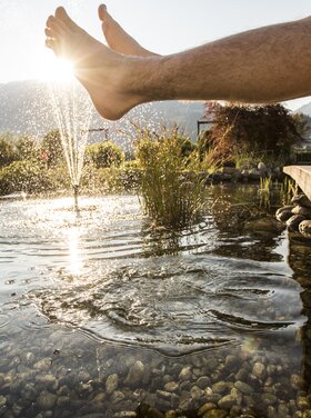 Feet dangle in the pond of the Hotel Theresa Zillertal's garden