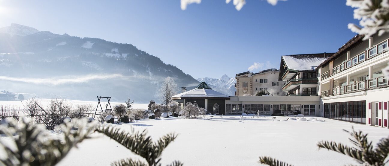The snowy winter garden offers a view of Hotel Theresa Zillertal