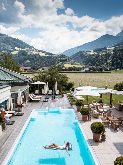 The view from the pool at Hotel Theresa Zillertal shows a woman on a lilo
