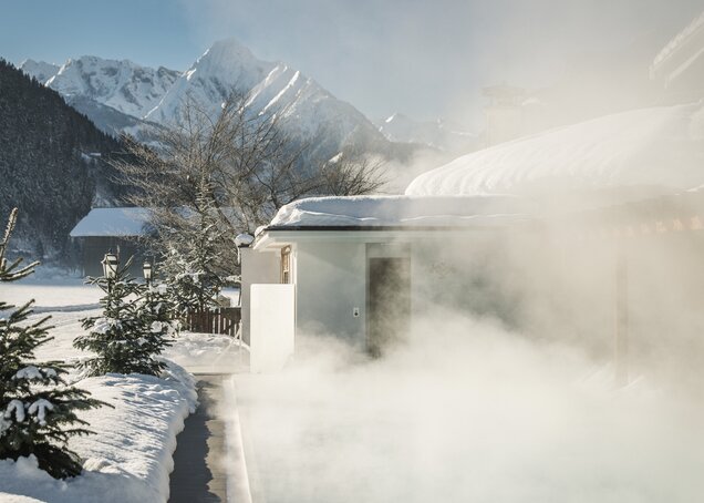 Wellnessurlaub beheizeiter Außenpool Winter Dampf Hotel Theresa im Zillertal Das Bild zeigt einen dampfenden Pool im Winter im Hotel Theresa im Zillertal