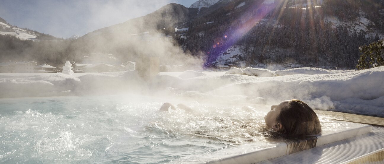 Eine Person entspannt im warmen Solepool im Winter im  Hotel Theresa