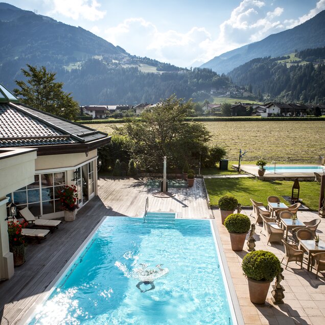 Eine Person taucht in den Außenpool vom Hotel Theresa im Zillertal