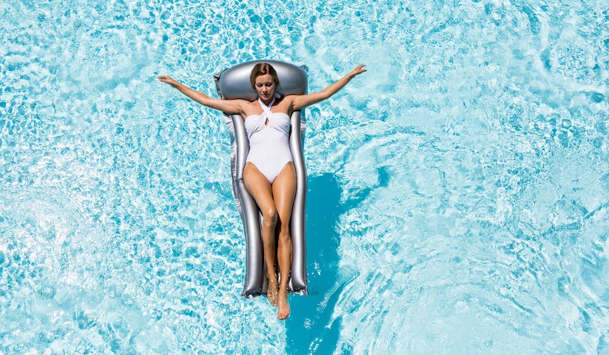 Eine Frau liegt auf einer Luftmatratze im Außenpool vom Hotel Theresa im Zillertal