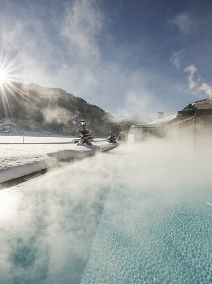 Wellnessurlaub im Zillertal Winterlandschaft mit Pool Hotel Theresa Winterliche Sonne scheint auf den Sportpool des Hotel Theresa im Zillertal