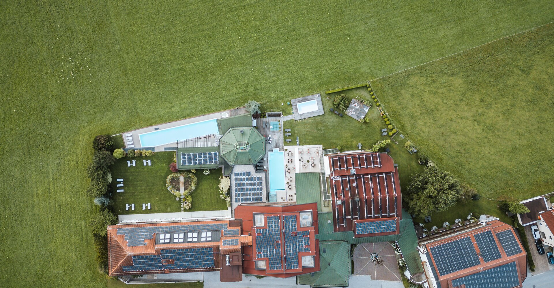 A drone shot of the wellness hotel Theresa Zillertal with photovoltaics is shown