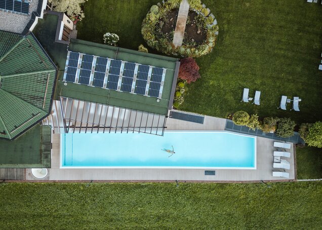 Drohnenaufnahme zeigt eine Person beim Schwimmen im Außenbecken des Wellnesshotel Theresa im Zillertal | © Carmen Huter
