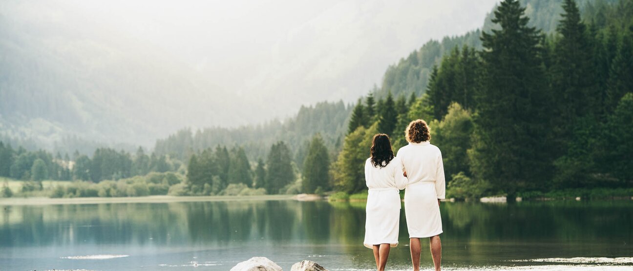 Ein Paar in Bademänteln steht am See im Hotel Theresa