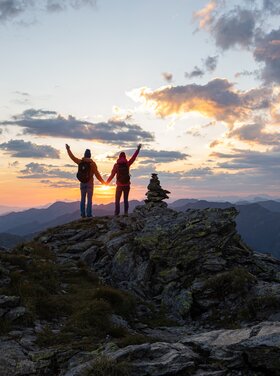 Two people stand on the Kreuzjoch in the Zillertal Arena at sunrise