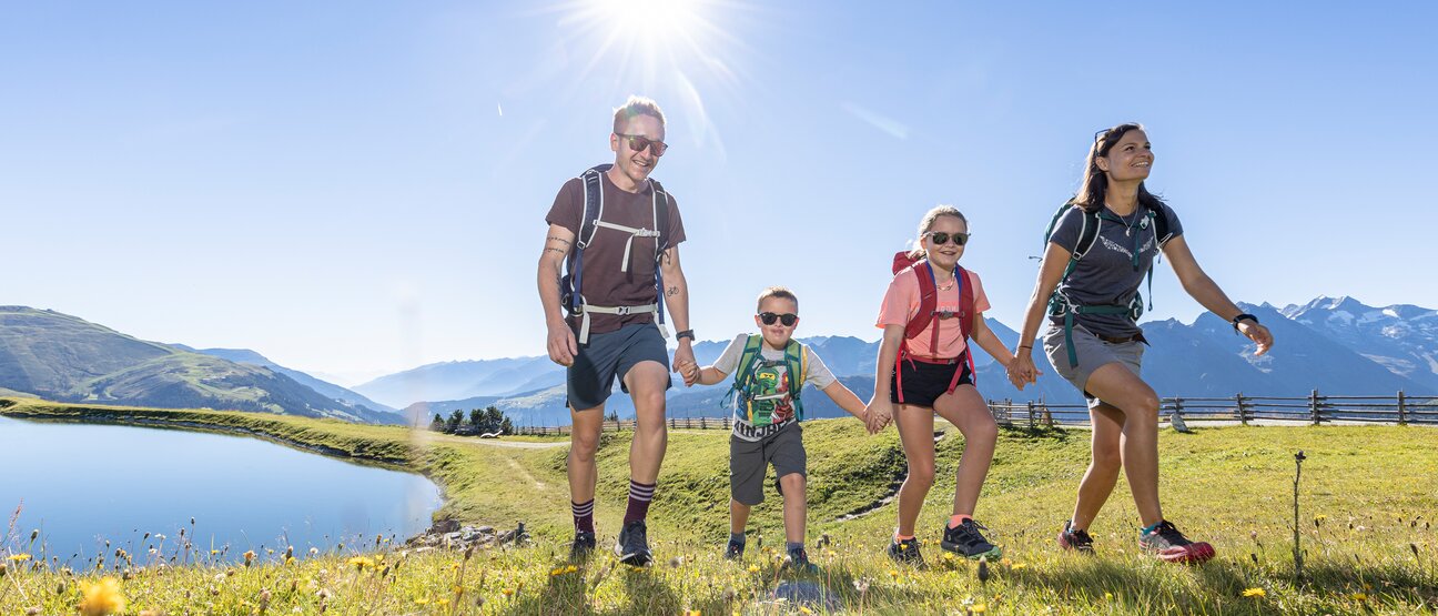 Eine Familie wandert am Isskogel in der Zillertal Arena an einem kleinen See vorbei