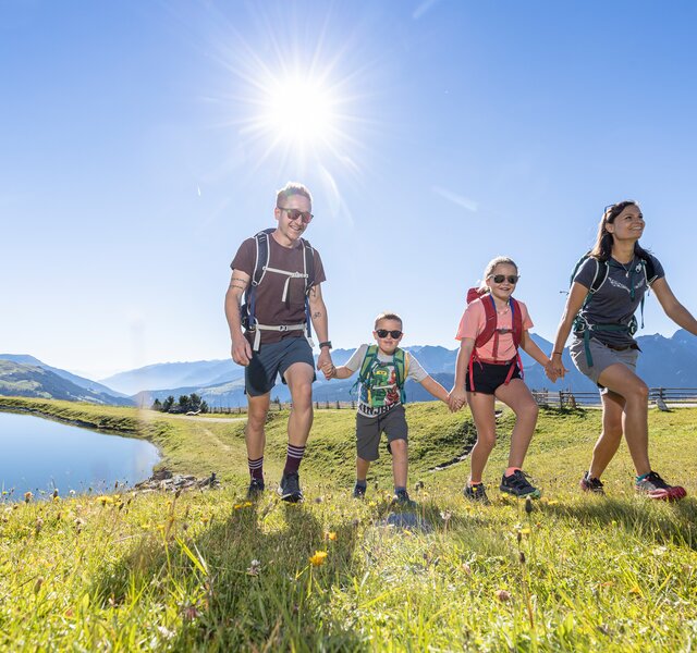 Eine Familie wandert am Isskogel in der Zillertal Arena an einem kleinen See vorbei