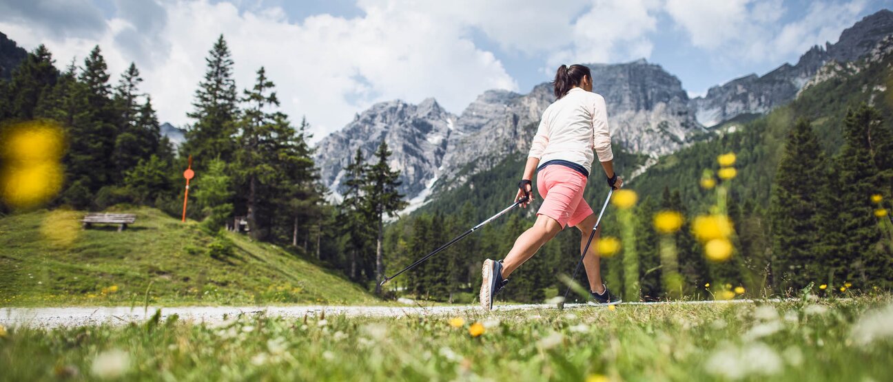 Eine Frau walkt mit Stöcken auf einem Weg im Zillertal beim Hotel Theresa