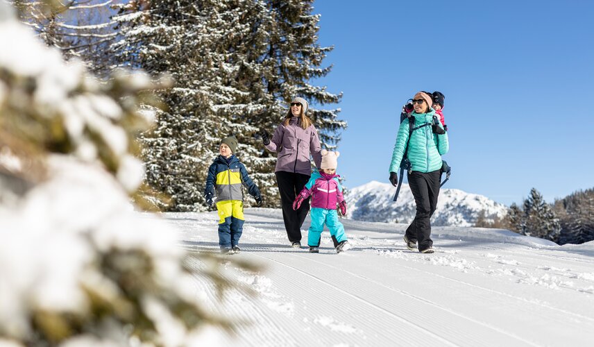 Eine Familie macht eine Winterwanderung auf der Almpromenade am Gerlosstein