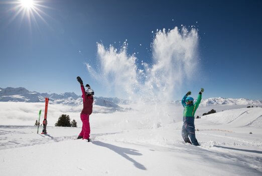 Im strahlenden Sonnenschein toben Kinder im Winter in der Zillertal Arena im Schnee