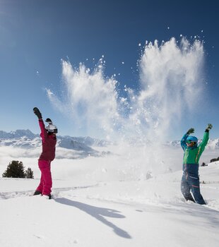 Im strahlenden Sonnenschein toben Kinder im Winter in der Zillertal Arena im Schnee