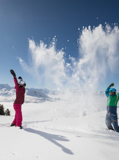 In the bright sunshine children romp in the snow in the Zillertal Arena in winter