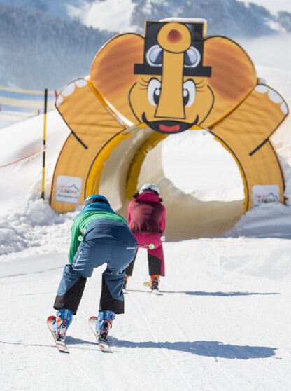 Children ski under an inflatable elephant